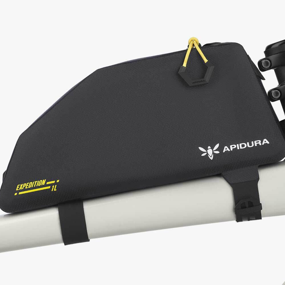 Black bikepacking bag with Apidura logo attached to a bicycle frame.